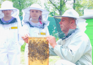 Dzieci pozują do zdjęcia z plastrem miodu