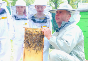 Dzieci pozują do zdjęcia z plastrem miodu