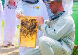 Dzieci pozują do zdjęcia z plastrem miodu