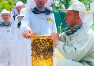 Dzieci pozują do zdjęcia z plastrem miodu