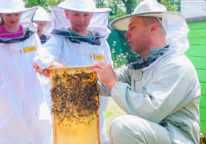 Dzieci pozują do zdjęcia z plastrem miodu