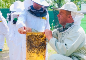 Dzieci pozują do zdjęcia z plastrem miodu