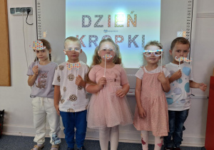 Czworo dzieci trzyma w ręku maskę na patyku zrobioną przez siebie