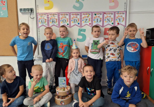 Chłopcy stoją na dywanie i pozują z Marysią do zdjęcia