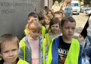 Grupa dzieci stoi przed budynkiem