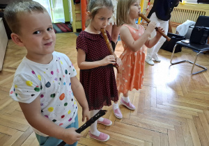 Troje dzieci próbuje grać na fletach