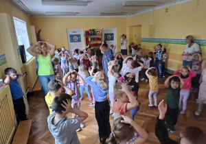 Dzieci uczestniczą w zabawie polegającej na wykonywaniu czynności, o których mówi piosenka