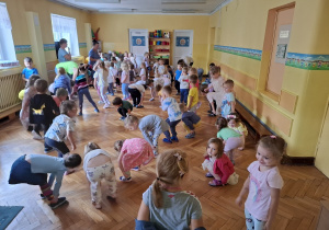 Dzieci uczestniczą w zabawie polegającej na wykonywaniu czynności, o których mówi piosenka