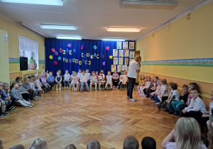 Dzieci siedzą dookoła sali gimnastycznej i czekają na rozpoczęcie uroczystości