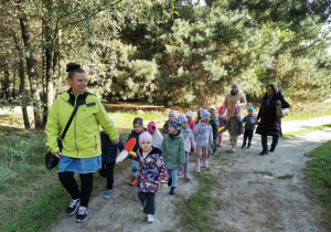 Grupa dzieci idzie za swoją panią trzymając węża spacerowego