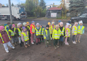 Grupa dzieci stoi na chodniku i czeka na autobus