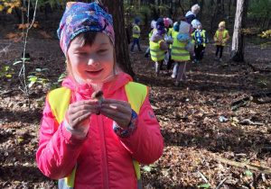 Dziewczynka trzyma w ręku znalezionego w lesie grzyba