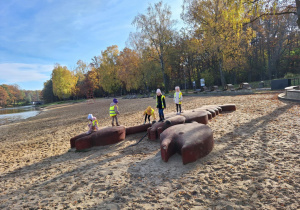Grupa dzieci stoi na rzeźbie raka na plaży w Arturówku