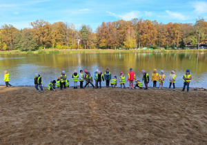 Dzieci stoją nad brzegiem stawu w Arturówku