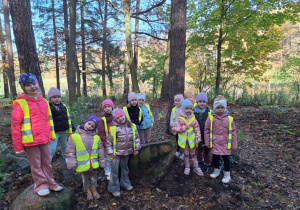 Dziewczynki w lesie pozują do zdjęcia stojąc na kamieniach