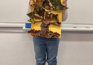 Dziewczynka pokazuje wykonane przez siebie jesienne drzewo