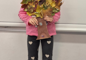 Dziewczynka pokazuje wykonane przez siebie jesienne drzewo