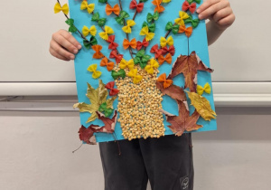 Chłopiec pokazuje wykonane przez siebie jesienne drzewo