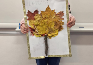 Dziewczynka pokazuje wykonane przez siebie jesienne drzewo