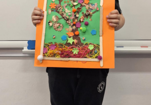 Chłopiec pokazuje wykonane przez siebie jesienne drzewo