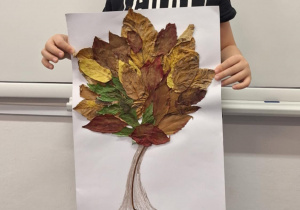 Chłopiec pokazuje wykonane przez siebie jesienne drzewo