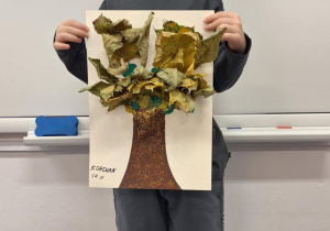 Chłopiec pokazuje wykonane przez siebie jesienne drzewo