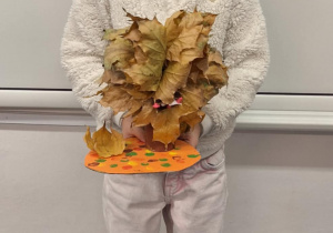 Dziewczynka pokazuje wykonane przez siebie jesienne drzewo