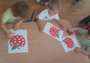 Dzieci wykonują pracę plastyczną stemplując palcem kropki