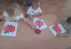 Dzieci wykonują pracę plastyczną stemplując palcem kropki