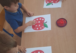 Dzieci wykonują pracę plastyczną stemplując palcem kropki