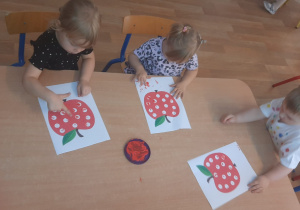 Dzieci wykonują pracę plastyczną stemplując palcem kropki