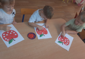 Dzieci wykonują pracę plastyczną stemplując palcem kropki