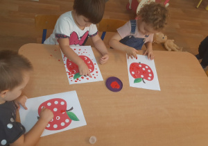 Dzieci wykonują pracę plastyczną stemplując palcem kropki