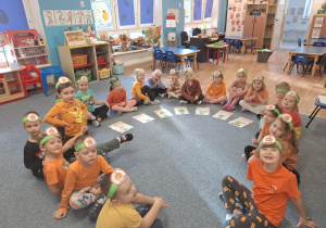 Dzieci siedzą na dywanie i uczestniczą w zabawie - Jak rośnie dynia