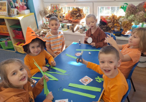 Grupa dzieci siedzi przy stoliku i wykonuje prace plasyczną