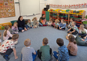 Dzieci siedzą na dywanie i słuchają opowiadania o jesieni