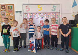 Grupa chłopców stoi na dywanie i pozuje do zdjęcia z Wojtkiem