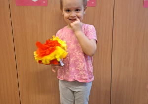 Dziecko pozuje do zdjęcia z pracą wykonaną wspólnie z rodzicami