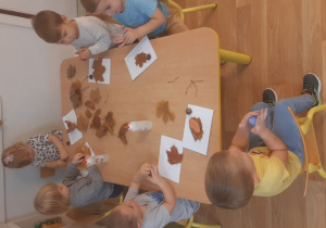 Dzieci wykonują pracę tematyczną na jesiennych warsztatach plastycznych