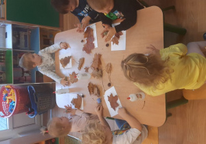 Dzieci wykonują pracę tematyczną na jesiennych warsztatach plastycznych