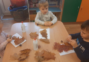 Dzieci wykonują pracę tematyczną na jesiennych warsztatach plastycznych