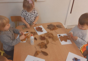 Dzieci wykonują pracę tematyczną na jesiennych warsztatach plastycznych