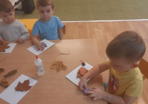 Dzieci wykonują pracę tematyczną na jesiennych warsztatach plastycznych