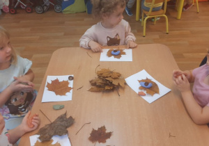 Dzieci wykonują pracę tematyczną na jesiennych warsztatach plastycznych