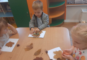 Dzieci wykonują pracę tematyczną na jesiennych warsztatach plastycznych