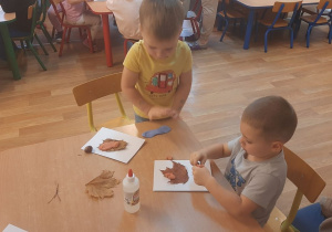 Dzieci wykonują pracę tematyczną na jesiennych warsztatach plastycznych