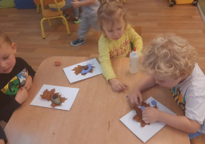 Dzieci wykonują pracę tematyczną na jesiennych warsztatach plastycznych