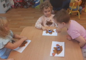 Dzieci wykonują pracę tematyczną na jesiennych warsztatach plastycznych