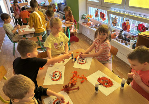 Dzieci wyklejają szablon dyni bibułą