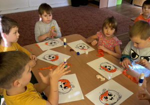 Dzieci wyklejają szablon dyni bibułą